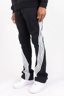 Black sweatpants with white side stripes, worn by a model with white sneakers against a plain white background. By Fresh N Fitted 