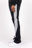 Black sweatpants with three white stripes down the side, worn by a model with white sneakers against a plain white background. By Fresh N Fitted 