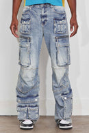 A person wearing extremely baggy light-wash blue denim cargo jeans with multiple patch pockets and oversized fit, paired with a blue and yellow top and black-and-white sneakers. By Fresh N Fitted.