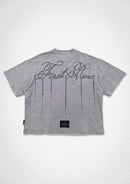 A light gray short-sleeve t-shirt shown from the back, featuring a large black cursive 'First Row' graphic with vertical dotted lines and a small black brand patch near the bottom hem. By Fresh N Fitted.