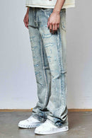 Person wearing distressed rhinestone light blue jeans and white sneakers on a plain background. By Fresh N Fitted.