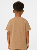 A child viewed from the back wearing a plain tan short-sleeve T-shirt against a light gray studio background.