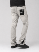 A person shown from the waist down wearing light gray washed denim jeans with distressed detailing and black platform shoes, photographed against a light gray studio background.