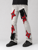 Light gray distressed denim jeans with red and black star-shaped patch designs and frayed details, shown on a model from the waist down wearing black shoes against a light gray studio background.