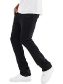 A person wearing slim-fit black jeans with a distressed pocket detail on the thigh, paired with a white t-shirt and white sneakers, shown from the waist down against a white background.