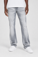 A person wearing light gray washed denim jeans with a white t-shirt and white sneakers, shown from the waist down against a light gray studio background.