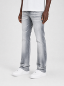 A person wearing light gray washed denim jeans with a white t-shirt and white sneakers, shown from the waist down against a plain light gray studio background.