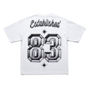 White short-sleeve T-shirt shown from the back, featuring the word 'Established' in black script above large 3D-style gray and black numbers '83' with small starburst accents. By Fresh N Fitted.