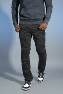 Person wearing a gray hoodie and black pants with red patches on a gray background. by Fresh n fitted