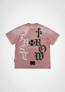 A pink short-sleeve t-shirt with a large graphic print on the back, featuring the word 'ROW' in dark green gothic letters and 'FIRST' in white gothic letters, along with paint splatter details, shown against a textured white background. By Fresh N Fitted.