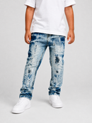 A child wearing light blue distressed denim jeans with a faded wash, paired with a white t-shirt and white sneakers, standing against a light gray studio background.