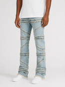 A person wearing light blue distressed denim jeans with diagonal frayed seam details, paired with a white t-shirt and white sneakers, shown from the waist down on a light gray studio background.