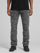 A person wearing distressed gray denim jeans with diagonal frayed seam details, paired with a black t-shirt and black sneakers, shown from the waist down on a light gray studio background.