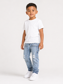 A young boy modeling a white short-sleeve t-shirt, light wash blue distressed denim jeans, and white sneakers against a plain white studio background.