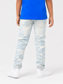A child shown from the back wearing light-wash distressed denim jeans with a white t-shirt and white sneakers, photographed against a plain light gray studio background.