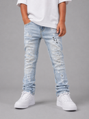 A child wearing light-wash, heavily distressed denim jeans with rips and frayed details, styled with a white t-shirt and white sneakers against a neutral gray studio background.