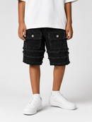 A person wearing black frayed denim shorts with large front flap pockets and silver snap details, paired with a white T-shirt and white sneakers, photographed against a light gray studio background.