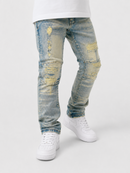 Light blue distressed denim jeans with yellow faded patches and ripped details, styled with a white t-shirt and white Nike Air Force 1 sneakers on a light gray studio background.