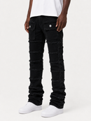 A person wearing black distressed denim jeans with horizontal frayed panel details and silver snap buttons on the thigh pockets, paired with a white t-shirt and white sneakers, against a light gray studio background.