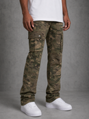 A person wearing slim-fit camouflage cargo pants with a white t-shirt and white sneakers, standing against a textured gray studio background.