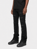 A person wearing black distressed skinny jeans with ripped details on the thighs and knees, paired with a black t-shirt and black sneakers, shown from the waist down on a light gray background.