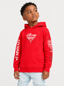 A young boy wearing a bright red pullover hoodie with white graphic prints on the chest and sleeves, paired with light blue jeans, photographed against a solid light gray background.