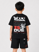 A child model shown from the back wearing a black graphic t-shirt and matching black shorts against a light gray studio background.