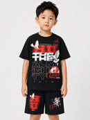 A young boy modeling a black graphic t-shirt and matching black shorts with red and white designs, set against a plain light gray background.