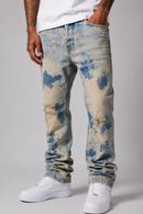A person wearing light-wash blue and beige acid-wash distressed jeans with ripped knees, paired with a white t-shirt and white sneakers, shown from the waist down against a light gray studio background. By Fresh N Fitted