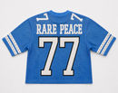A blue short-sleeve jersey shown from the back, featuring the words 'RARE PEACE' and the number '77' in white with black outlines. The sleeves have white stripes with small silver star-like details. By Fresh N Fitted