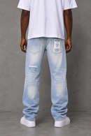 A person shown from the back wearing light-wash distressed jeans with a white T-shirt and white sneakers, standing against a gray concrete wall. By Fresh N Fitted.