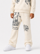 A child wearing cream-colored sweatpants with black classical-style illustrations and white sneakers, shown from the waist down against a light gray studio background.