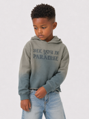 A young boy wearing a gray ombre hoodie with 'SEE YOU IN PARADISE' printed on the chest, paired with light blue jeans, against a plain light gray background.