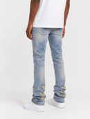 A person shown from the back wearing light-wash blue distressed jeans with ripped details near the cuffs, a white t-shirt, and white sneakers against a plain light gray studio background.