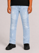A person wearing light-wash distressed denim jeans with patchwork biker-style seams, shown from the waist down against a plain light gray studio background.