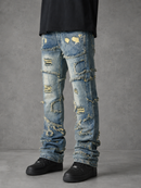 Light blue heavily distressed denim jeans with ripped details, frayed edges, and patches, worn by a model with a black shirt and black shoes against a gray studio background.