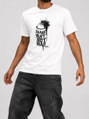 A man wearing a white crew-neck t-shirt with a black spray can graphic and the text 'MAKE ART NOT WAR' printed on the chest, paired with dark gray paint-splattered jeans, against a light gray studio background. available at fresh n fitted men's tees