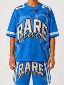A person wearing a bright blue oversized graphic t-shirt and matching shorts with 'RARE peace' lettering, photographed against a light gray studio background. By Fresh N Fitted.