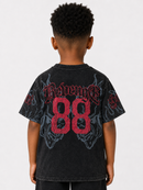A child viewed from the back wearing a faded black graphic T-shirt with red gothic lettering, large red '88' numerals, and gray wing-like artwork on a light gray studio background.