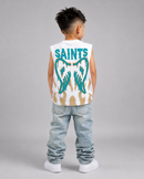 A young boy viewed from behind wearing a sleeveless white tank top with a large teal and beige graphic on the back, paired with light-wash jeans and white sneakers, against a solid gray studio background.