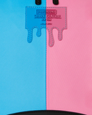Close-up of a backpack or bag body split vertically into bright cyan-blue on the left and pink on the right, with a stitched embossed label reading Speedround Shark Central New York near the top and black trim at the bottom.