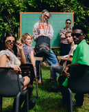 Group of people sitting outdoors with a chalkboard in the background