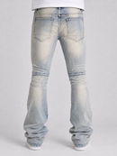 Rear view of a person wearing light-wash blue flared jeans with a faded white t-shirt and white sneakers, set against a plain light gray studio background.
