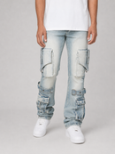 A person wearing light-wash blue cargo jeans with multiple flap pockets and distressed details, paired with a white t-shirt and white sneakers, photographed against a light gray studio background.