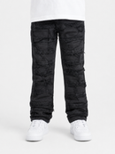 Black distressed ripped jeans with a raw, layered frayed texture, shown on a model from the waist down wearing white sneakers against a light gray background.
