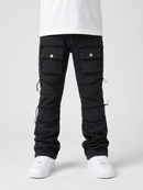 A person shown from the waist down wearing black distressed cargo-style pants with flap pockets and white sneakers against a light gray studio background.
