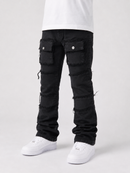 Black distressed cargo-style jeans with frayed details and flap pockets, shown on a model from the waist down wearing a white t-shirt and white sneakers against a light gray studio background.