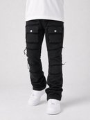 Black distressed cargo pants with ripped details and frayed edges, shown on a model from the waist down wearing white sneakers against a light gray studio background.