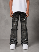 A child wearing black denim jeans covered in silver sequins, styled with a white t-shirt and white sneakers, standing against a gray textured studio background.