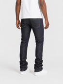 Rear view of a person wearing slim-fit dark indigo jeans, a white t-shirt, and white sneakers against a light gray studio background.